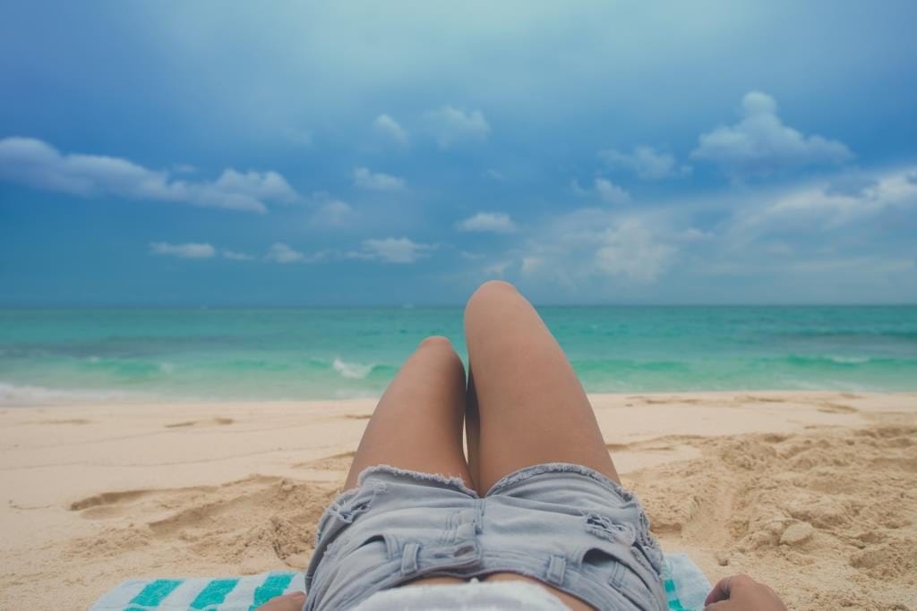 WEB_Stokpic-Lifestyle Girl laying on Beach With Jean Shorts